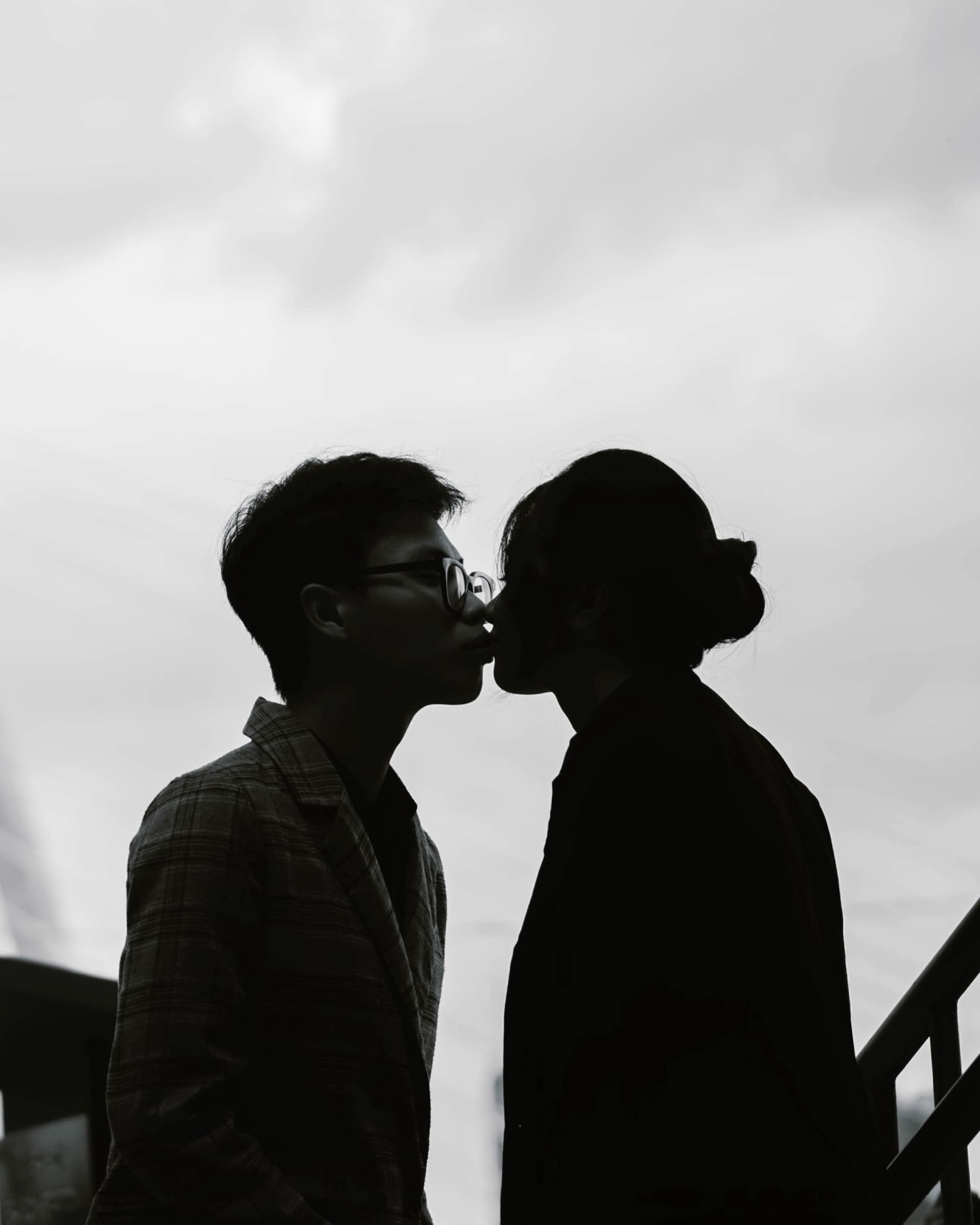 Couple kissing under a cloudy sky