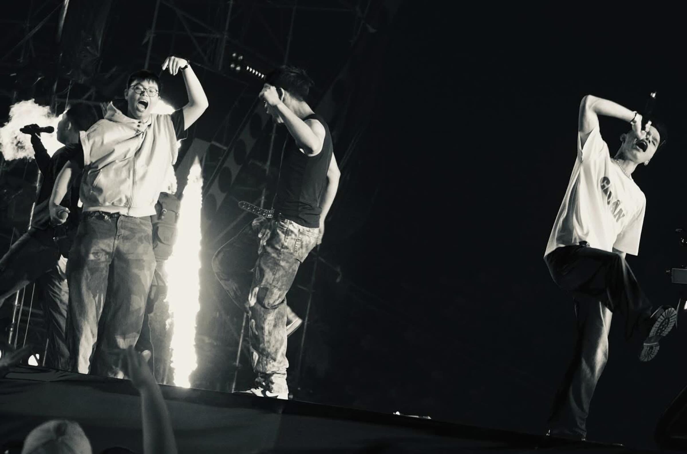 Performers caught in motion on a concert stage in black and white