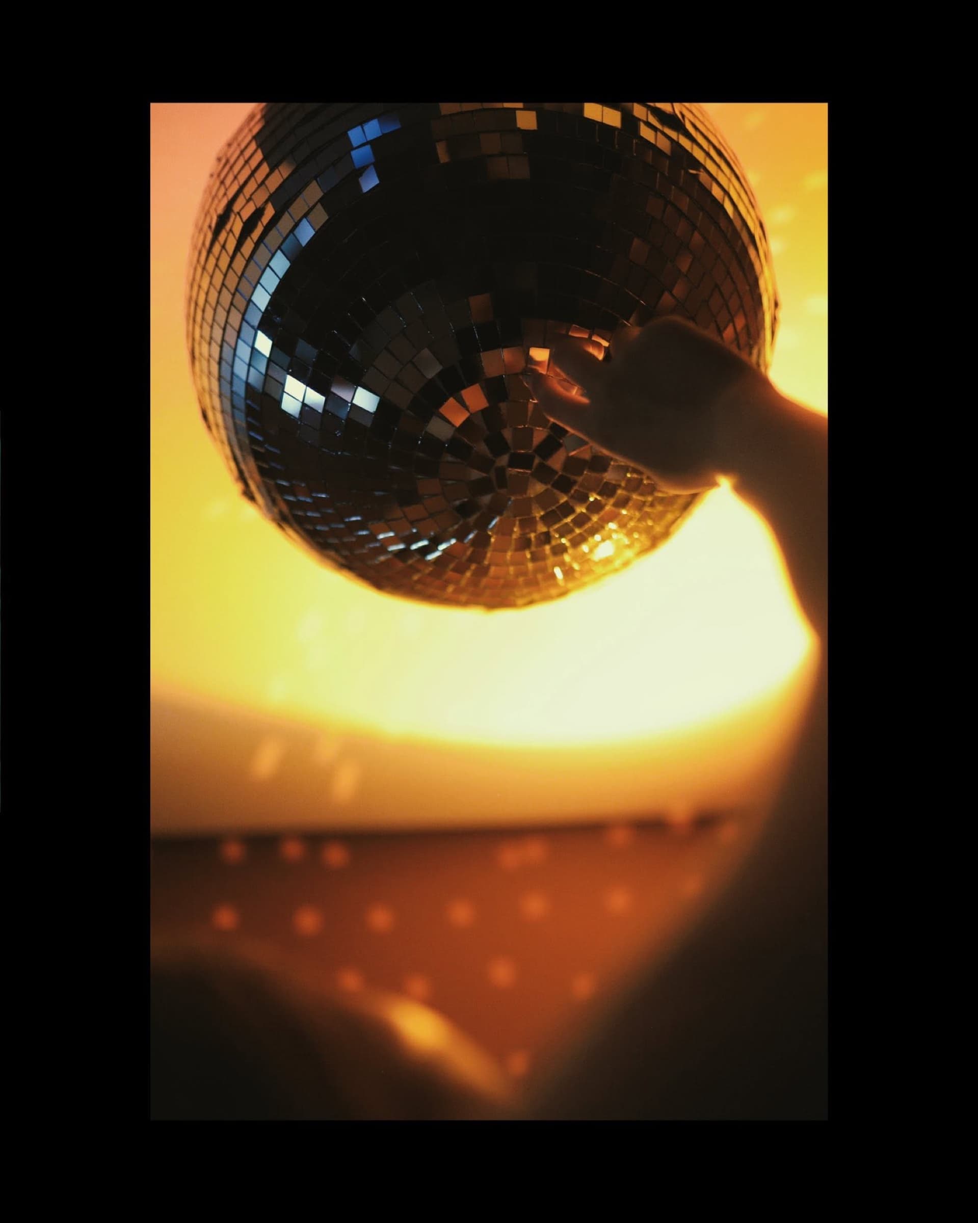 Hand holding a mirrorball in warm amber light