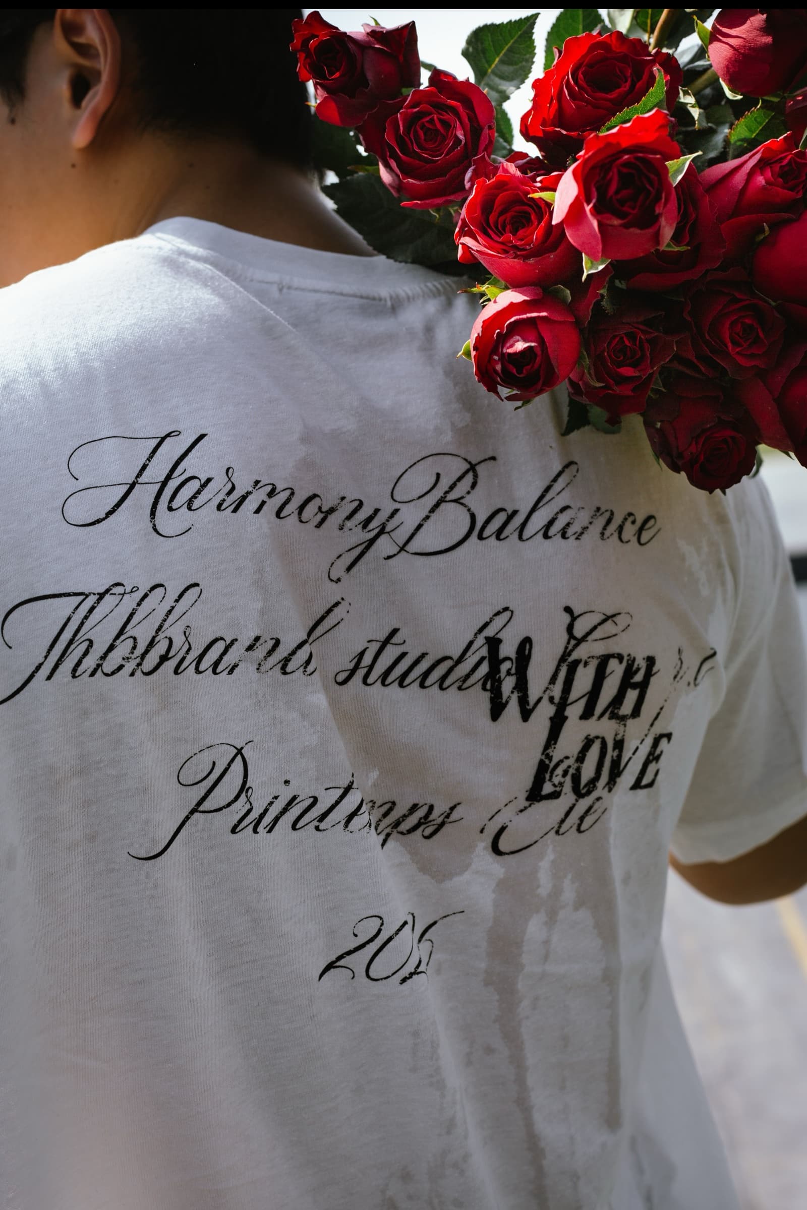 Editorial detail of red roses against a typographic white shirt